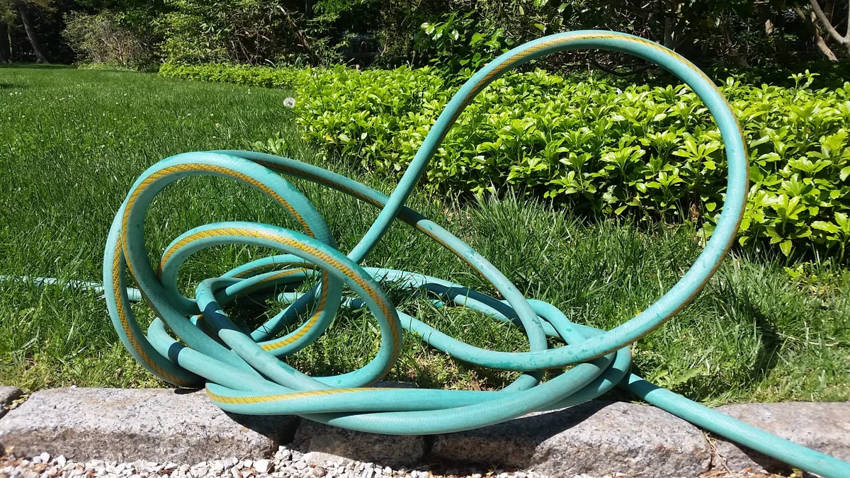 garden hose tangled on grass, frustration, German garden