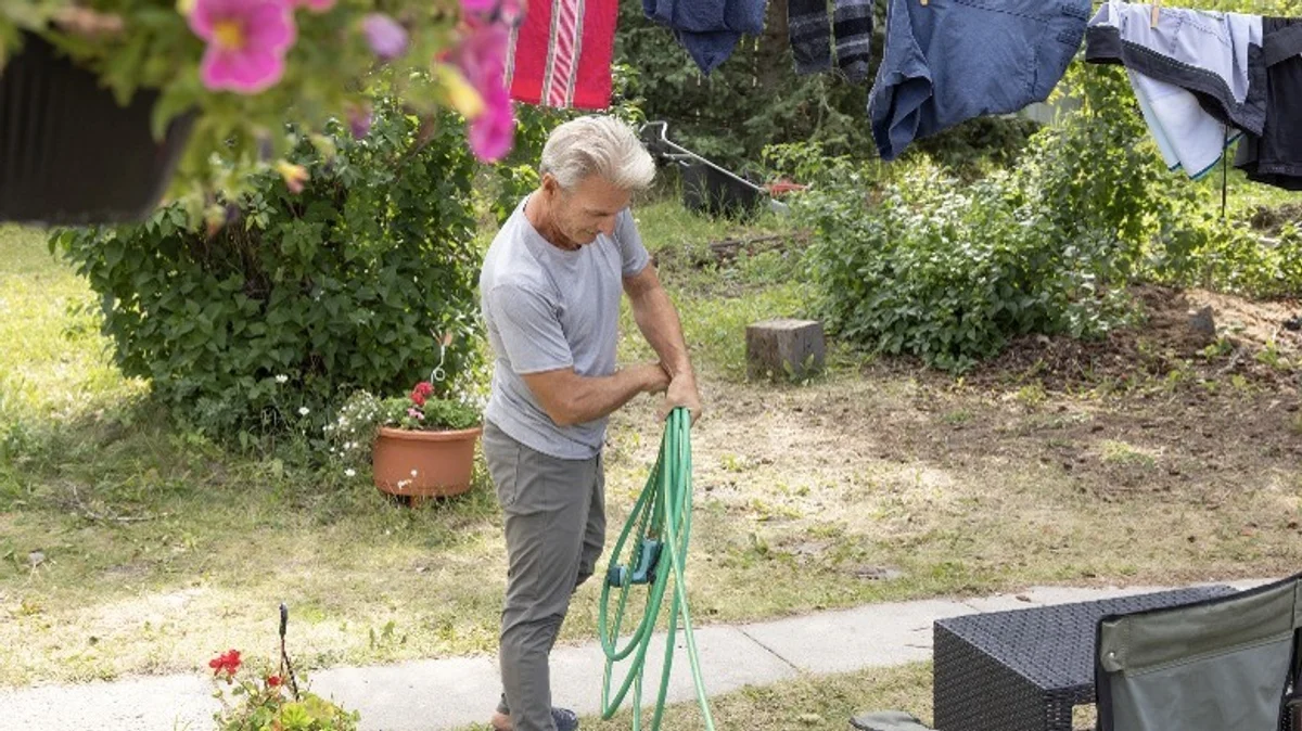 person winding garden hose figure 8, hands only, German backyard
