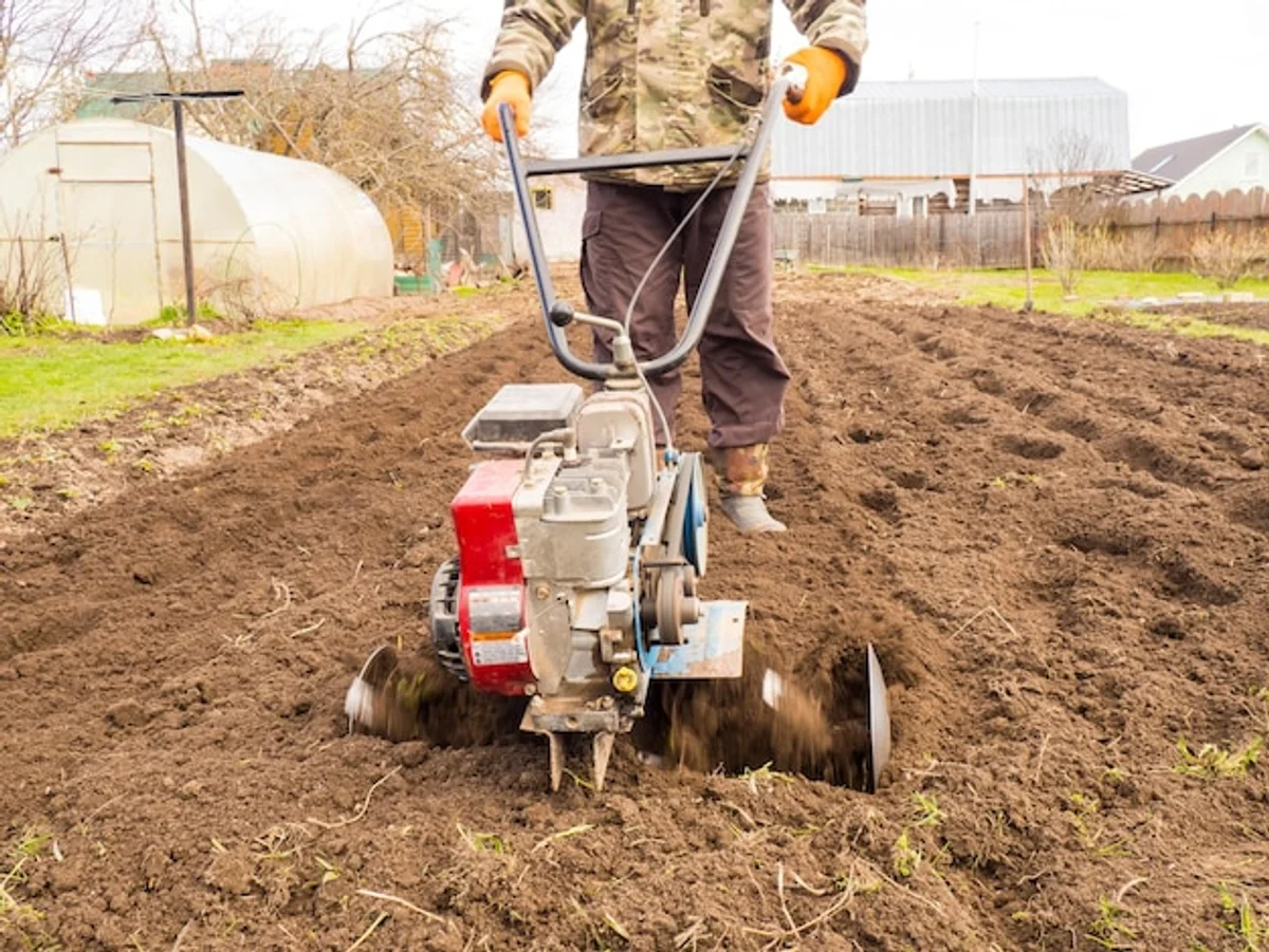 modern gardener using electric tiller in vegetable garden