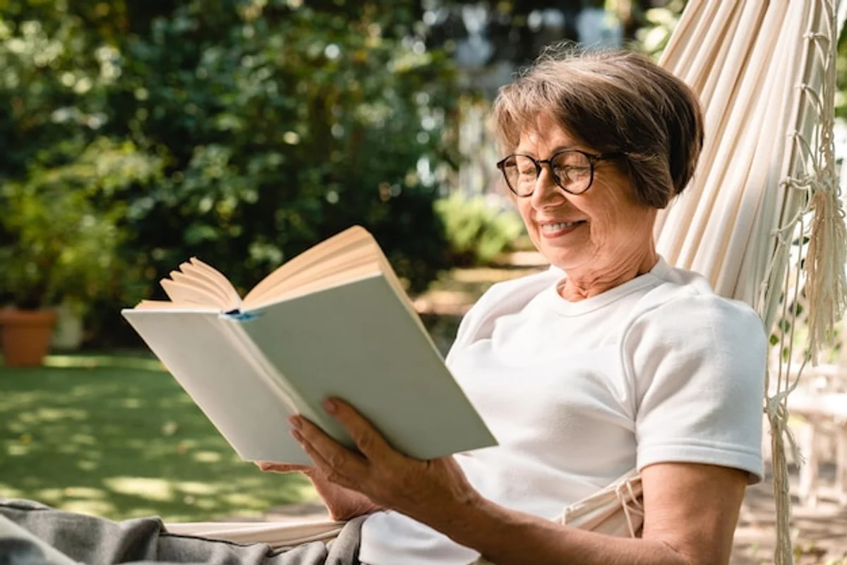 senior woman relaxing with indoor plants reading book